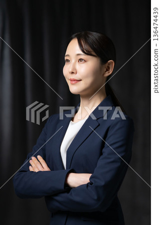 Woman in a suit with arms folded Woman in a suit with arms folded 136474439