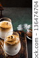 Creamy whipped Dalgona coffee served in elegant glasses on a rustic wooden board with coffee grounds 136474704