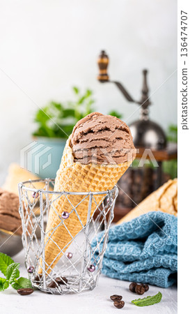 Chocolate ice cream cone in a decorative basket with fresh mint leaves and coffee beans Chocolate ice cream cone in a decorative basket with fresh mint leaves and coffee beans 136474707