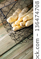 Fresh white asparagus spears in a wire basket on rustic wooden table with natural light 136474708