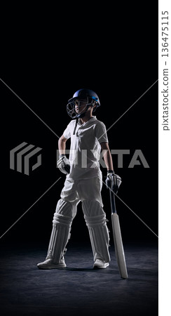 Young cricket player standing with bat on dark studio background. Young cricket player standing with bat on dark studio background. 136475115