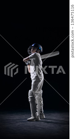 Young cricket player standing with bat on shoulder in studio. Young cricket player standing with bat on shoulder in studio. 136475116