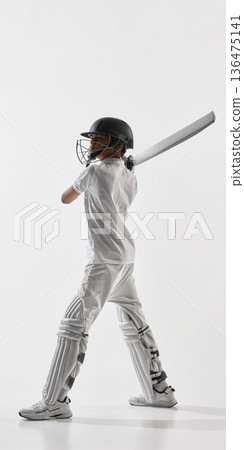 Young cricket player standing with bat after swing isolated on white background. Young cricket player standing with bat after swing isolated on white background. 136475141