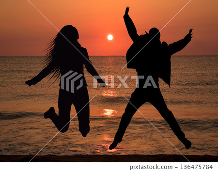 Couple silhouettes jumpin in the air, sunset sky - freedom, love concept Couple silhouettes jumpin in the air, sunset sky - freedom, love concept 136475784