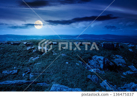 grassy alpine meadow in carpathian mountain landscape at night. sharp rocks and huge boulders among lush grass on rolling hills in full moon light. open space scenery for wanderlust and exploration 136475837