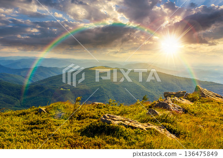 beautiful summer landscape in mountains at sunset. stones on grassy alpine meadow in evening light. view from the edge of a hill. wonderful sunny weather with rainbow. fluffy clouds on the sky beautiful summer landscape in mountains at sunset. stones on grassy alpine meadow in evening light. view from the edge of a hill. wonderful sunny weather with rainbow. fluffy clouds on the sky 136475849