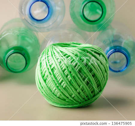 Green yarn ball and plastic bottles representing recycling 136475905
