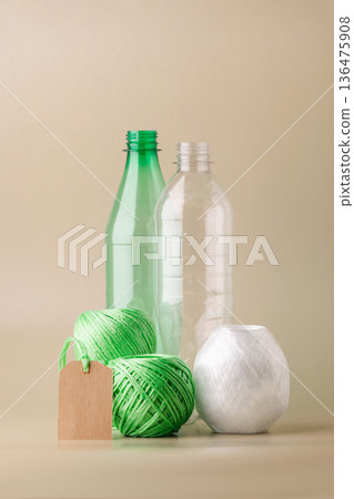 Empty plastic bottles, several skeins of polyester thread, blank label promoting recycling, sustainability, eco-friendly production. Green lifestyle, eco-technologies 136475908