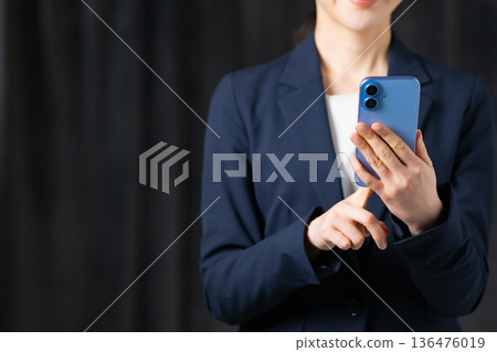 Business woman operating a smartphone Business woman operating a smartphone 136476019