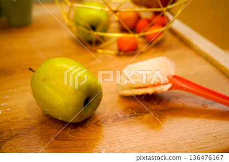 The washed fruits are in a vase and next to them is a brush with which they were washed. 136476167