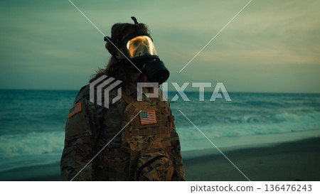 Soldier in toxic environment salutes at Memorial Day celebration near ocean Soldier in toxic environment salutes at Memorial Day celebration near ocean 136476243
