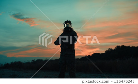 Silhouette of a Lone Soldier Wearing a Gas Mask at Sunset on the Beach Silhouette of a Lone Soldier Wearing a Gas Mask at Sunset on the Beach 136476245