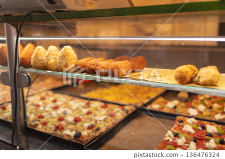 Traditional Italian street food including pizza slices and fried snacks displayed in a bakery showcase in the historic center of Rome. Italy Traditional Italian street food including pizza slices and fried snacks displayed in a bakery showcase in the historic center of Rome. Italy 136476324
