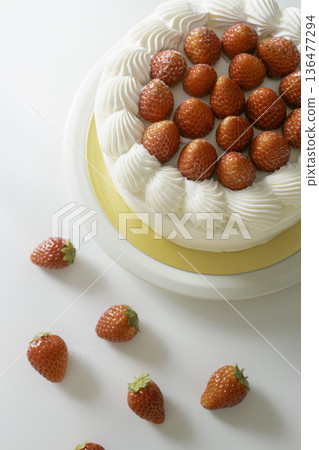 Close-up of strawberry shortcake: A homemade decorated cake with strawberries scattered on a white background 136477294