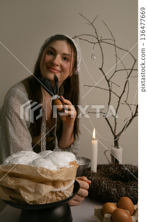 Preparing for Easter evening, she decorates the table with colorful eggs and candles, creating cozy festive atmosphere. 136477669