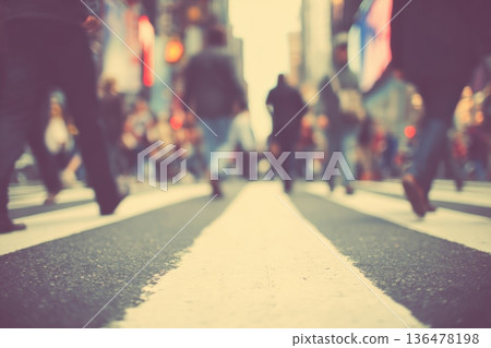 Crowds of people stroll across a bustling crosswalk, illuminated by colorful traffic lights in a vibrant city scene as dusk approaches 136478198