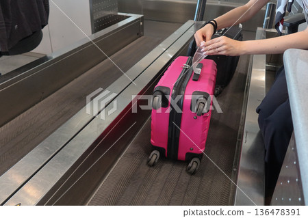 A pink suitcase with a baggage tag attached at an airport check-in counter at Milano Malpensa Airport (MXP) A pink suitcase with a baggage tag attached at an airport check-in counter at Milano Malpensa Airport (MXP) 136478391
