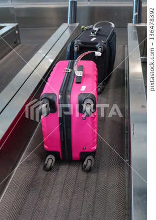 A pink suitcase with a baggage tag at an airport check-in counter at Milano Malpensa Airport (MXP) 136478392