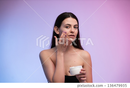Woman using a moisturizing face cream to nourish and hydrate her skin, creating a healthy and glowing complexion as part of her beauty and self-care regimen Woman using a moisturizing face cream to nourish and hydrate her skin, creating a healthy and glowing complexion as part of her beauty and self-care regimen 136479935
