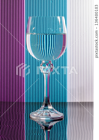 Still life with a glass goblet containing liquid on a colored background 136480183