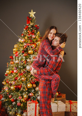 Couple shares joy by the Christmas tree with gifts Couple shares joy by the Christmas tree with gifts 136480420