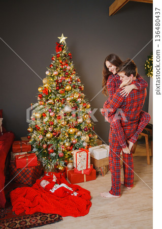 Couple celebrates holiday in front of Christmas tree Couple celebrates holiday in front of Christmas tree 136480437
