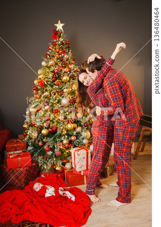 Couple in PJs celebrating Christmas with baby 136480464