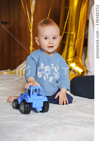 Happy toddler playing with blue toy truck indoors Happy toddler playing with blue toy truck indoors 136480552