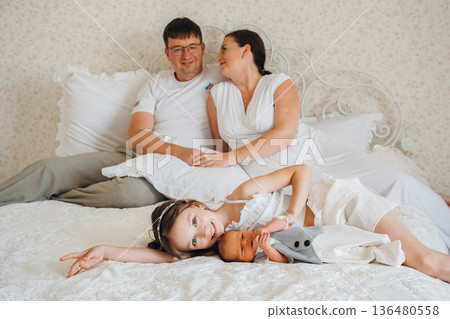 Family enjoys time together on bed with newborn Family enjoys time together on bed with newborn 136480558