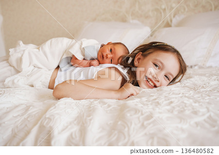 Sister plays with baby brother on bed in the morning Sister plays with baby brother on bed in the morning 136480582