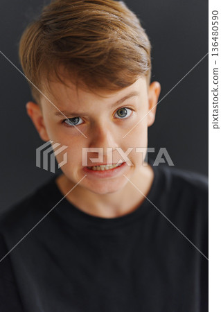 Boy shows a strong expression with a serious face indoors Boy shows a strong expression with a serious face indoors 136480590