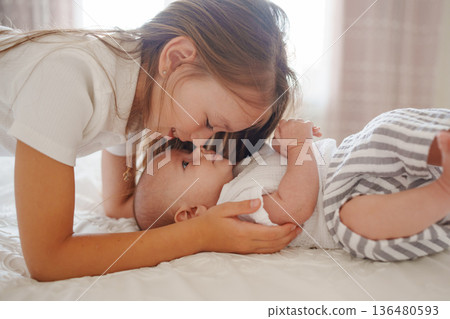 Sister bonding with her baby brother at home Sister bonding with her baby brother at home 136480593