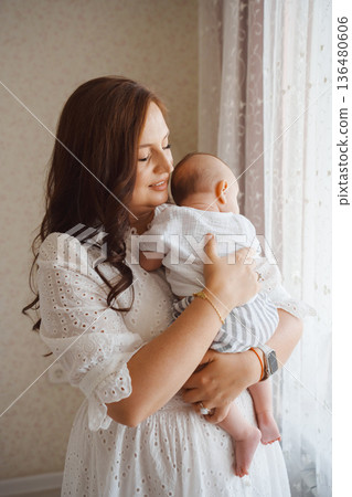 Mother lovingly holding her baby in a bright room Mother lovingly holding her baby in a bright room 136480606