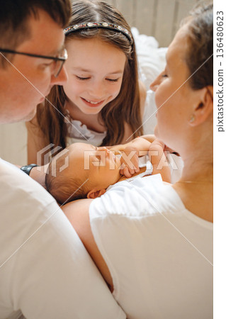 Family shares moment with newborn and sister indoors 136480623