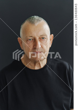 Older man with short hair poses against a dark background Older man with short hair poses against a dark background 136480643