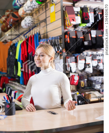 Friendly store assistant working at sportswear shop counter Friendly store assistant working at sportswear shop counter 136480670