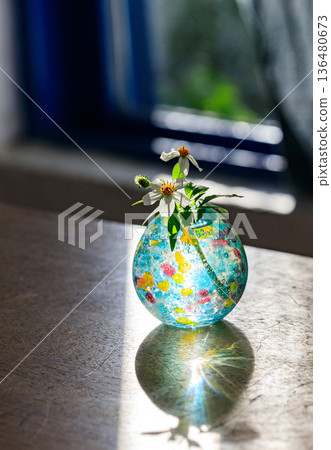 A glass vase and a small flower catching the light A glass vase and a small flower catching the light 136480673