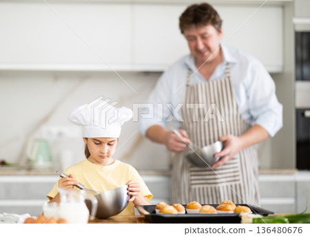 Father and daughter preparing muffins in kitchen Father and daughter preparing muffins in kitchen 136480676