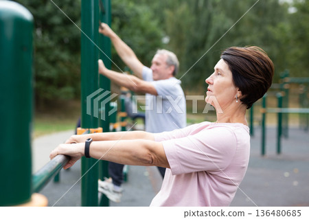 Healthy lifestyle in retirement - an elderly woman does a workout on the sports ground in park. 136480685
