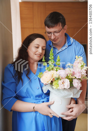 Couple smiles while holding a flower bouquet indoors 136480706