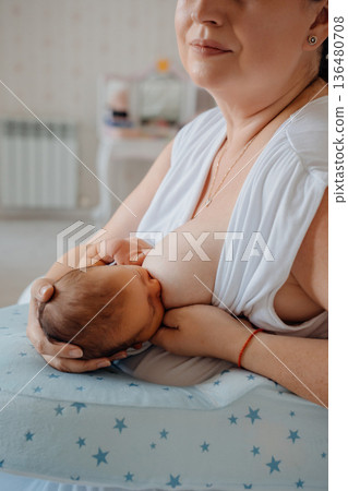 Woman breastfeeding baby in cozy indoor space 136480708