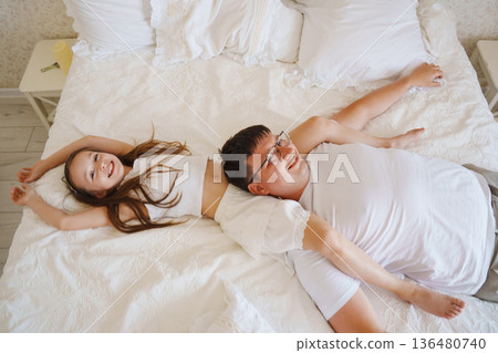 Father and daughter play on bed in morning light Father and daughter play on bed in morning light 136480740