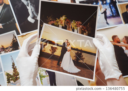 hands in white gloves and Beautiful printed wedding photos. hands in white gloves and Beautiful printed wedding photos. 136480755