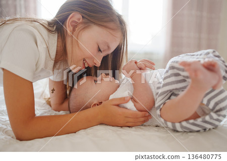 Sister plays with baby brother at home on a sunny day Sister plays with baby brother at home on a sunny day 136480775