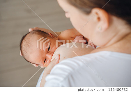 Mother feeds baby in quiet indoor setting Mother feeds baby in quiet indoor setting 136480782