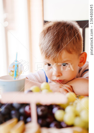 Child looks at fruit with curiosity in kitchen 136480845