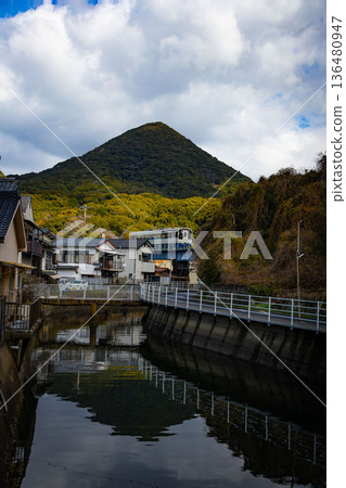 一列當地火車正駛過河邊房屋上方的鐵路橋。 136480947