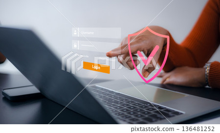 Business woman logging in on laptop with virtual shield icon, representing cyber security, data privacy protection, secure network access, and digital identification technology. 136481252