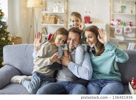 Happy family waving hands celebrating Christmas at home having online video call 136481936