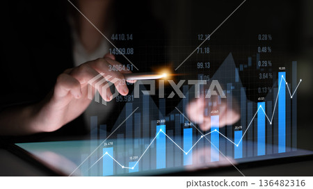 Business professional analyzing data trends on a digital tablet with graphs and statistics in a dark environment highlighting financial growth Scalp 136482316